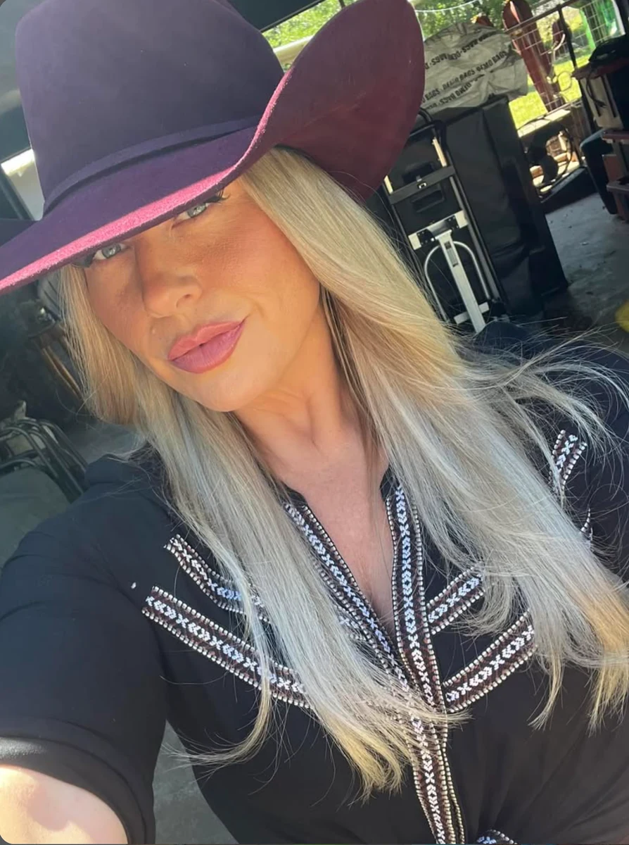 A woman wearing a broad-brimmed burgundy western hat with an understated band