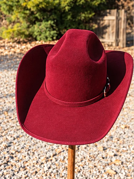 A deep burgundy western hat with a sculpted crown, lifted brim edges and a slim matching band