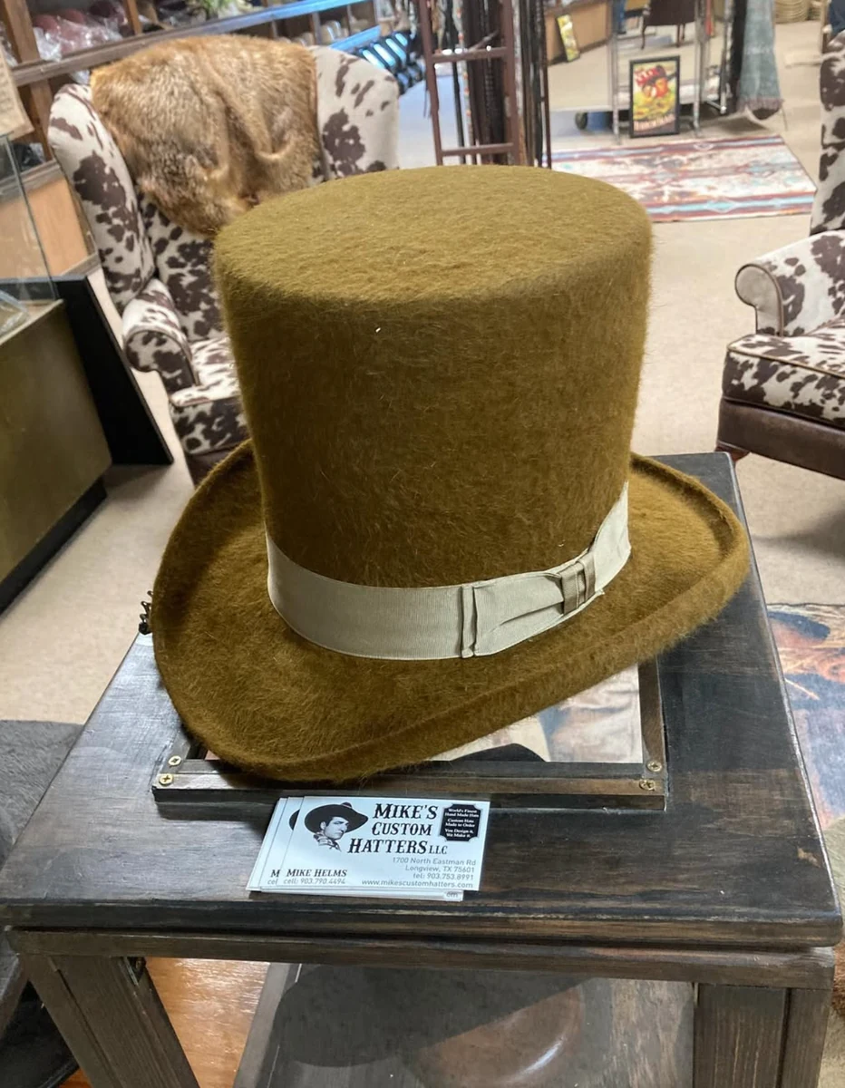 A textured olive hat with a tall flat-topped crown and contrasting pale ribbon band on display